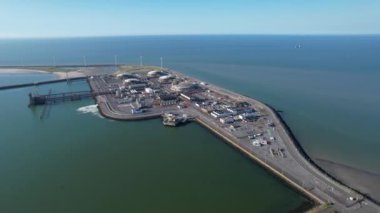 Zeebrugge limanının sanayi tesisleri ve rüzgar türbinleriyle çevrili gemileriyle dolu hava görüntüsü..