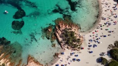 Sardunya 'da, kristal berrak turkuaz su, beyaz kum ve güneşli bir günün tadını çıkaran insanlarla dolu güzel bir sahil manzarası..