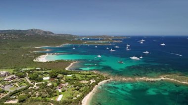 Turkuvaz suları, beyaz kumlu plajlar, yemyeşil yemyeşil ve ufku benekli lüks yatların yer aldığı Sardinya 'nın çarpıcı kıyı şeridi..