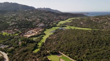 İtalya 'nın Sardinya kentindeki Pevero Golf Sahasının manzarası, küçük bir gölet ve yemyeşil ağaçlar..