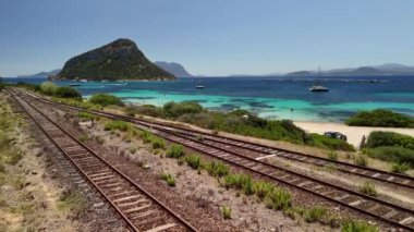 İtalya 'nın Sardunya kentindeki çarpıcı bir turkuaz plaja giden tren raylarının resimli görüntüsü..