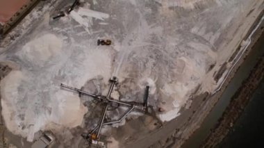 İtalya 'nın Sardinya sahilindeki tuz tepsisinin kuş bakışı görüntüsü. Yükleyici ve taşıyıcı bantlarla tuz taşıyorlar..
