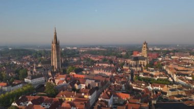 İnsansız hava aracı görüntülerinde Bruges, Belçika şafak vakti çarpıcı tarihi çatılar ve ikonik kilise kuleleri bu büyüleyici şehirde güzel bir manzara yaratıyor.