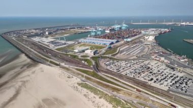 Belçika 'daki Zeebrugge lojistik merkezinin hava görüntüsü büyük bir otopark, liman tesisleri ve kumlu bir plaj gösteriyor..