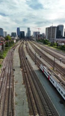 Güneşli bir günde Brüksel Nord tren istasyonunun yanındaki raylarda bir tren durur. Raylar boş ve şehrin ufuk çizgisi uzaktan görülebiliyor..