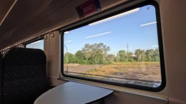 Güneşli bir sabahta boş bir otoparkın yanından bir tren geçer..