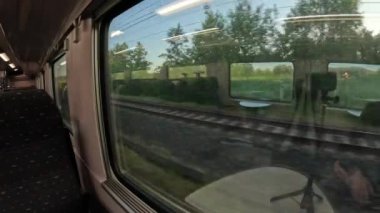 Bir tren kırsal bir bölgeden geçiyor, batan güneş doğaya sıcak bir parıltı saçıyor..