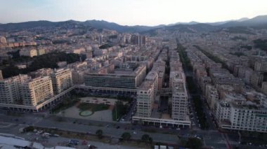 Aerial views capture the stunning architecture and layout of Genova, showcasing the vibrant cityscape as the sun begins to set over the mountains.