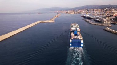 Bir kargo gemisi gelir ve Ceneviz Limanı 'nın hareketli limanına bu önemli denizcilik merkezindeki faaliyetleri vurgulayan sayısız konteynırı boşaltır..