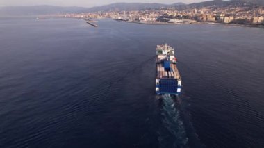 Geniş bir kargo gemisi yaklaşıyor ve konteynırlarını kalabalık limana boşaltmaya hazır bir şekilde Cenova limanına varıyor..