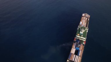 Konteynırları boşaltmak için Cenova limanına bir kargo gemisi yanaşıyor ve rıhtıma yanaşıyor. Günün hareketli denizcilik aktivitesine katkıda bulunuyor..