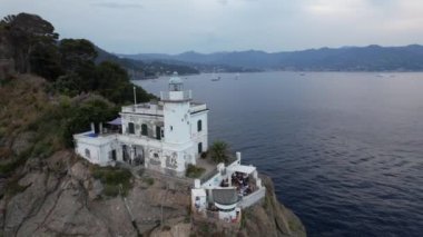 Güneş batarken Portofino Deniz Feneri 'nin çarpıcı mimarisine tanık olun. İtalyan sahil şeridine ve sakin sulara güzel bir ışık saçıyor..