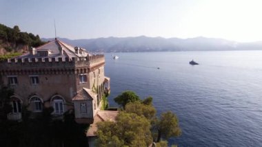 Açık güneşli bir günde, İtalya kıyılarında tünemiş, denizin ve etrafındaki dağların çarpıcı manzarasını gösteren nefes kesici villayı keşfedin..
