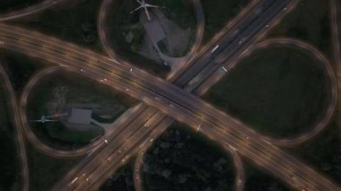 Akşamüstü yoğun trafik saatlerinde trafik ışıklarının aydınlattığı yoğun otoyol kavşağında arabalar yol alır..