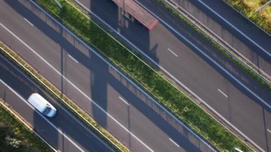 Parlak güneş ışığı altında otoyol boyunca giden arabalar yoğun trafik ve şerit birimlerini gösteriyor..