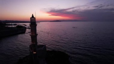 Girit, Chania 'nın nefes kesici güzelliğini hisset. Güneş ikonik deniz fenerinin arkasında batarken sakin denizin üzerinde büyülü bir parıltı yayıyor. Renkler ufukta dans eder.