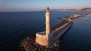 Güneş, Chania 'nın üzerinde batarken, deniz feneri dalgalar ve sakin denizlerle çevrili, Cretes sahillerinde büyüleyici bir akşam atmosferi yaratıyor..