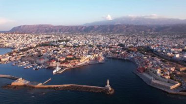 Girit, Chania 'nın büyüleyici güzelliğine tanık olun. Renkli binalar limana yakın, arka planda dağlar yükseliyor ve güneş ufukta batıyor. Kasabayı altın renklerle yıkıyor..