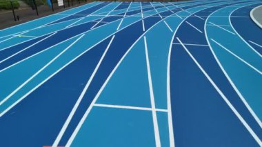 Beyaz çizgili ve yeşil bantlı bir spor stadyumunun mavi koşu pisti manzarası.