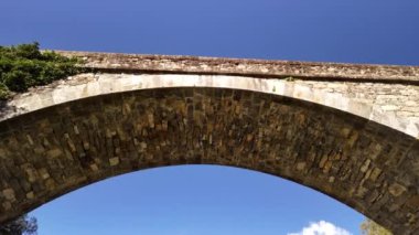 Korsika 'da canlı bir mavi gökyüzüne karşı dizilmiş antik taş kemer yolunun çarpıcı detaylarını keşfedin. Tarihi ve mimariyi gözler önüne seriyor..