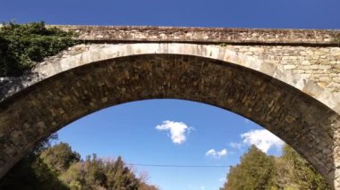 Korsika 'daki antik bir taş köprünün güzelliğini keşfedin, çarpıcı mavi gökyüzüne ve sonbahar yapraklarına karşı..