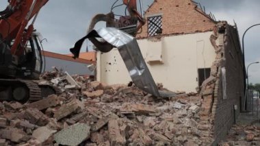 Ağır makineler, şehir manzarasında terk edilmiş bir binayı aktif olarak yıkıyor ve bir enkaz bulutu yaratıyor..