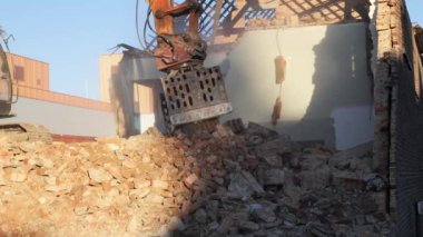İşçiler terk edilmiş bir yapıyı yıkmaya başladılar, temiz gökyüzüne karşı moloz ve enkazı ortaya çıkardılar..