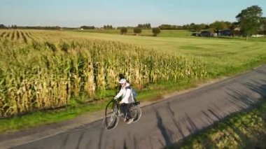 Sabah işe giderken tarlalarla çevrili sakin bir kır yolunda bisiklet süren bir adamı izleyin..