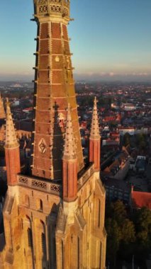 Güneş batarken Brugge 'ün büyüleyici güzelliğine tanık olun. Tarihi kiliseyi ve çevresini aydınlatıyor..