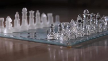 Temiz satranç taşları titizlikle cam bir tahtaya yerleştirilmiş. Karmaşık tasarımlar ve ustalıkla sergileniyor..