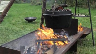Bir tencere, açık havada yanan bir ateşin üzerinde kaynıyor ve kırsal alanda pişirme deneyimini güçlendiriyor..