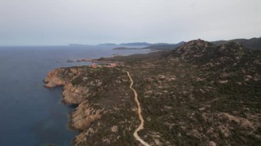 Sardunya 'nın çarpıcı kıyı manzaralarını deneyin. Yumuşak, bulutlu bir gökyüzünün altında dolambaçlı yolları keşfedin..