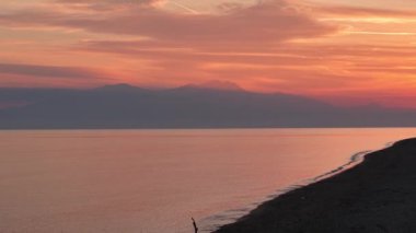 Gün batımının nefes kesen renklerini deneyimlemek sahildeki sakin sulara yansıyarak huzurlu bir atmosfer yaratıyor..
