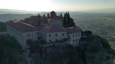 Şafak sökerken uçurumlara tünemiş Meteoras antik manastırlarının çarpıcı güzelliğini tecrübe edin..