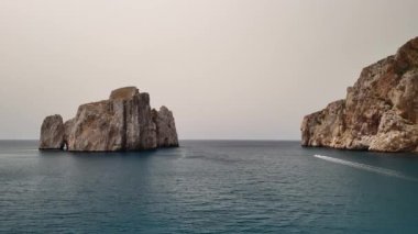 Sardinya 'daki Porto Flavia' nın nefes kesici kıyı manzarasına tanık olun. Gün batımında kayalık oluşumlarını ve sakin sularını gözler önüne seriyor..