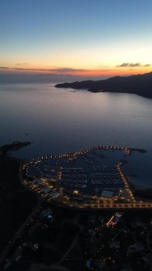 Sardunya limanında gün batımının tadını çıkarın. Şehir ışıklarının sakin suyu yansıttığı yerde..