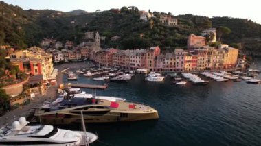 İtalyan Rivierası boyunca uzanan Portofino, günbatımında dönüşüm geçirir, sakin suları yansıtan renkli binalarını sergilerken lüks tekneler yavaşça sallanır..