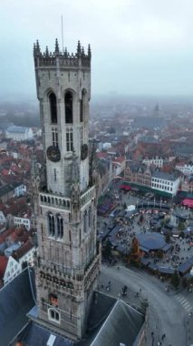 Tatil sezonunda büyüleyici Bruges şehrini keşfedin. Simgesel çan kulesi sisin üzerinde yükselirken, hareketli Noel pazarı aşağıdaki meydanı şenlikli tezahüratlarla dolduruyor..