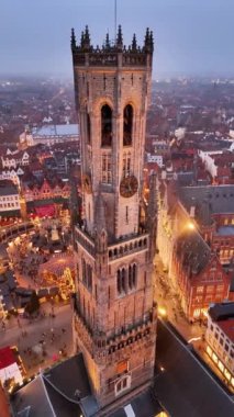 Bruges, yüksek çan kulesinin altındaki Noel pazarı canlandıkça kış harikalar diyarına dönüşüyor. Ziyaretçiler keyifli tezgahların ve akşamları yanıp sönen ışıkların keyfini çıkarıyorlar..