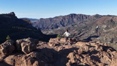 Bir müzisyen, Gran Canaria dağlarında, uçurumların ve vadilerin nefes kesici manzaralarıyla çevrili bir piyanoda gösteri yapıyor. Huzurlu atmosfer güzel melodileri arttırır..