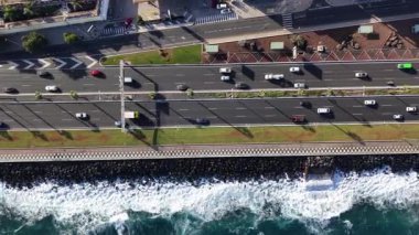 Las Palmas de Gran Canaria 'nın çarpıcı kıyı şeridi boyunca dalgalar kıyıya vururken arabaların geçitte gezindiğini hissedin..