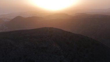 Engebeli tepelerin ardında güneşin soluk kesici bir görüntüsü volkanik arazide sıcak renkler bırakıyor. Huzurlu atmosfer, düşüncelere ve korkuya davetiye çıkarır..