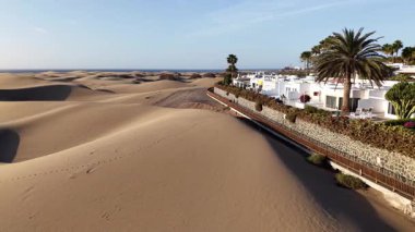 Gran Canaria 'nın nefes kesici hava perspektifini keşfedin, zarif kıyı konutlarının yanında altın kum tepeleri sergilenmektedir. Doğa ve mimarinin güzelliği açık bir gökyüzü altında uyumludur..