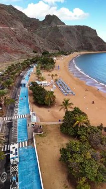 Tenerife 'deki Teresitas Sahili' nin nefes kesici manzaralarını tecrübe edin. Altın kumları, ferahlatıcı mavi suları ve yemyeşil palmiye ağaçlarını sergileyin. Güneşli günlerde rahatlamak ve rahatlamak için mükemmel..