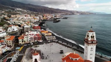 Tenerife 'nin nefes kesici hava manzarasını keşfedin. Sahildeki renkli binaları, arka plandaki görkemli dağları ve gökyüzünün altında parlayan berrak suları ortaya çıkarın..