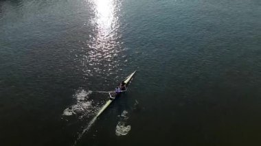 Güneş batarken sakin bir suda kürek çeken bir insan yüzeyde güzel yansımalar yaratıyor. Bu huzurlu an, doğanın güzelliğini sessiz bir yerde yakalar..