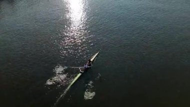 Bir kayakçı, yüzeyde parıldayan güneş ışığı yansımalarıyla çevrili huzurlu bir su yolunda zarifçe süzülür. Sakin atmosfer deneyimi güçlendirir..