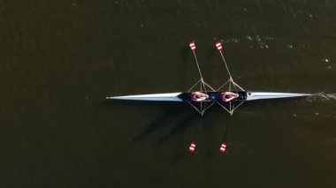 İki sporcu gün batımında antrenman yaparken sakin sularda parlak bir tekneyle kürek çekiyorlar. Sakin ortam, yeteneklerini birleştirirken anın güzelliğini arttırır..
