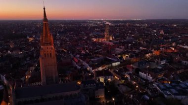 Güneş şehrin üzerinde batarken Belçika, Brugge 'ün çarpıcı hava manzarasını keşfedin. İkonik kulelere, tarihi binalara ve altın ışıkla yıkanmış büyüleyici manzaraya hayran kaldım..