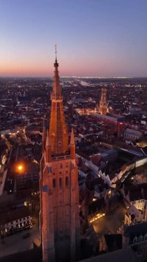 Brugge, Belçika 'nın nefes kesici hava manzarasını gece çökerken tecrübe edin. Şehir ışıkları, etkileyici kuleler ve büyüleyici caddelerle tarihi mimarisini aydınlatıyor..